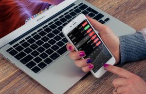 How to develop our business through digital marketing? A person hold a phone in front laptop