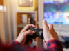 Is gaming is beneficial for us? A person holding video game remote in front of tv