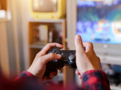 Is gaming is beneficial for us? A person holding video game remote in front of tv