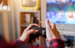 Is gaming is beneficial for us? A person holding video game remote in front of tv