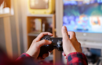 Is gaming is beneficial for us? A person holding video game remote in front of tv