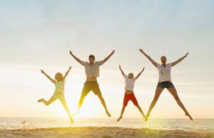 Enjoy your life in an entertainment-filled world Family doing star jumps on beach